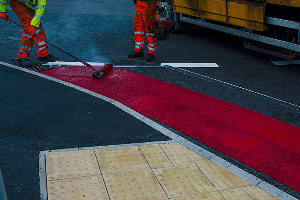istock Road construction activity with roadworker applying hot melted white paint for traffic lines demarcation on new road surface 2251017504
