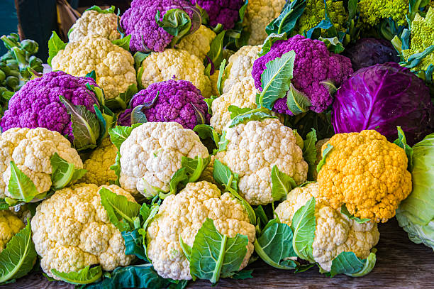 Yellow, purple and white heads of fresh cauliflower along with incidental green and purple cabbage offered for sale at a Lancaster County, Pennsylvania farmers' market