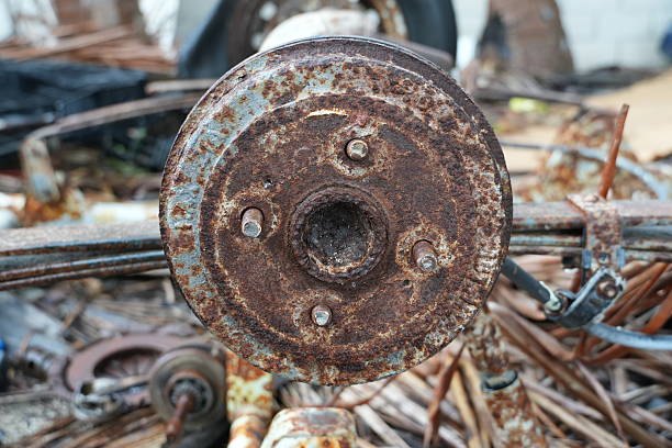 A rusty metal wheel sits amidst a pile of discarded industrial waste in a scrapyard, telling a story of neglect and environmental impact.