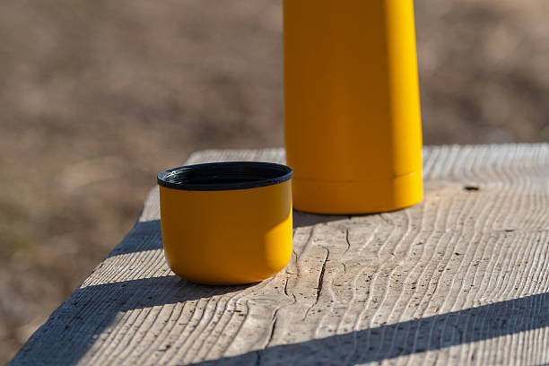 Yellow thermos flask on wooden table