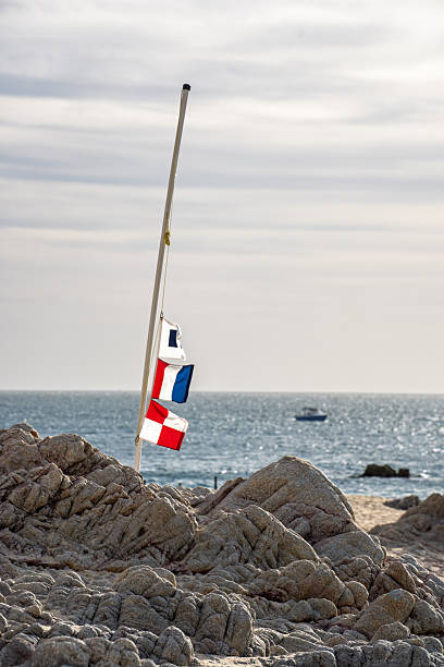 istock A flag pole with a flag on it is on a rocky beach 2251032108