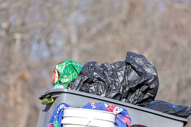 istock Clothes And Household Items In Overflowing Outdoor Trash Container. 2251032702
