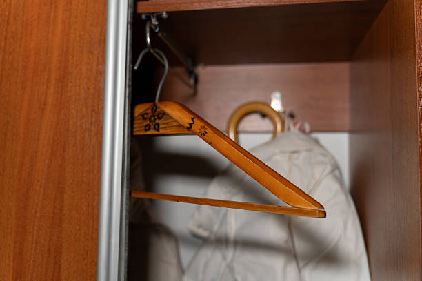 An open wardrobe with wooden hangers holding a light-colored jacket and an umbrella, capturing an everyday home storage scene. The image reflects organization, clothing care, and domestic lifestyle. High quality photo