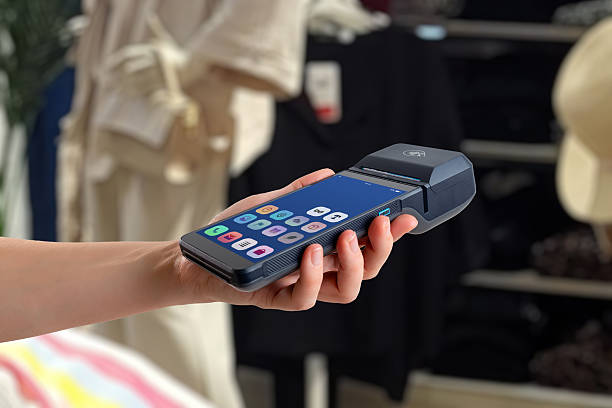 istock Hand holding smart POS terminal with app interface visible on screen, used in a modern boutique shopping environment 2251037772