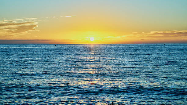 istock sunset on the beach and the sun is setting on the horizon 2251040912