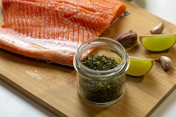 Fresh Raw Salmon Fillet with Lime, Garlic and Herbs on Cutting Board – Healthy Cooking Ingredients, Seafood Preparation and Clean Eating Concept