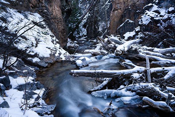 Fresh snow dusting and wilderness creek flowing through rocky canyon. Looking downstream.