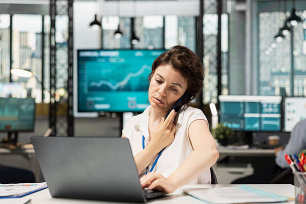 istock Female professional talking on phone and using laptop in workplace 2251050242
