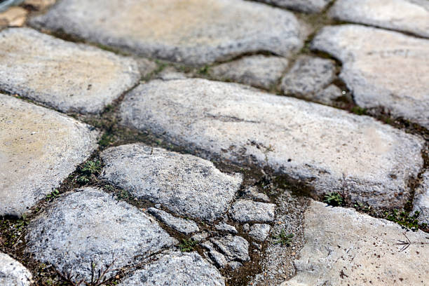 Close-up view of stone paving, showing detailed natural textures, subtle color variations, and the irregular surface pattern of the stones. Ideal as a background or architectural material reference.