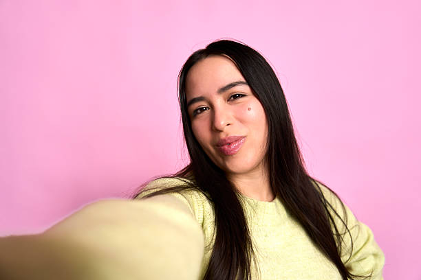 istock Young woman taking selfie with pink background 2251052001