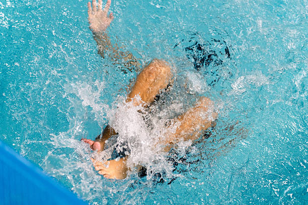 Child's legs and arms thrashing in blue pool water, creating splashes during a swimming lesson or water play