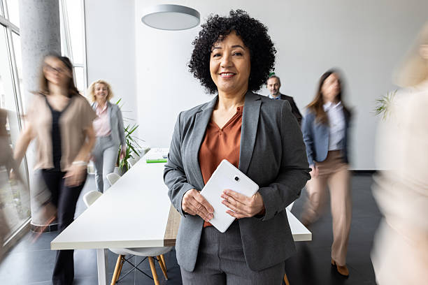 istock Happy woman holding tablet in fast-paced office environment 2251059731