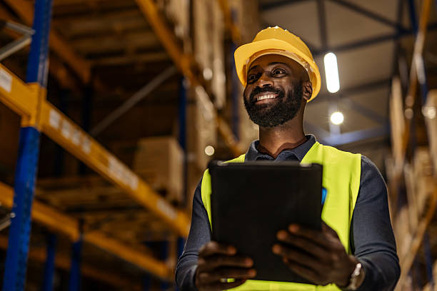 istock Smiling Warehouse Worker with Tablet and Reflective Vest in Modern Facility 2251059797