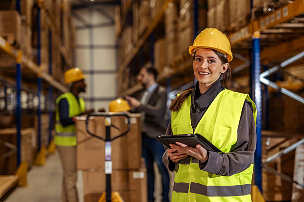istock Warehouse Workers Wearing Hard Hats and Safety Vests Collaborating 2251059818