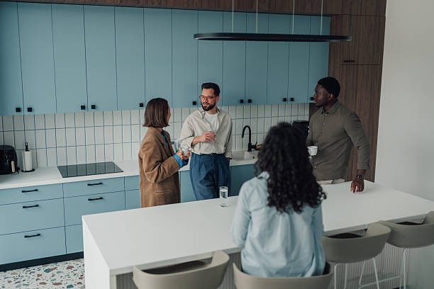 istock Coworkers socializing and communicating during coffee break in modern office kitchen 2251060951