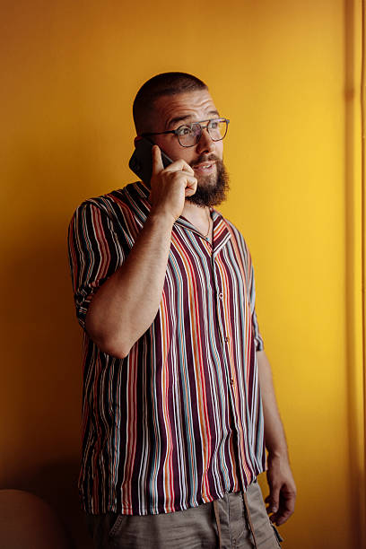 istock Man talking on the phone against a yellow wall 2251069487