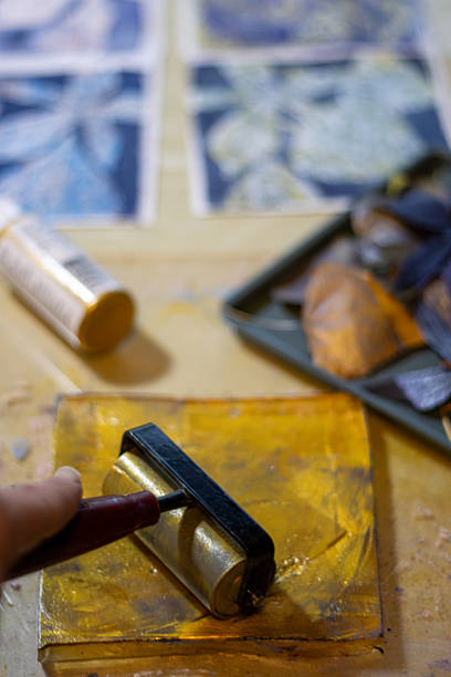istock Hand rolling golden acrylic onto gelli plate in printmaking sess 2251080152