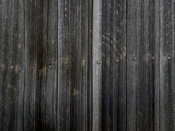 Dark gray wooden planks show weathered texture with nails in a horizontal line