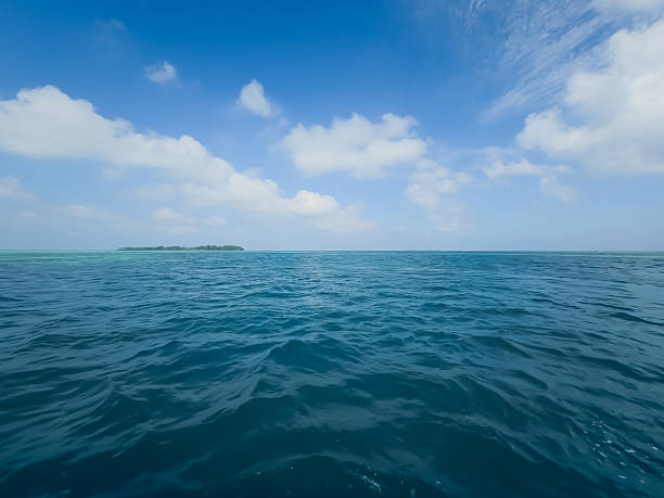 Expansive water fills the frame leading to a bright sky dotted with soft clouds, capturing serenity and vastness for inspirational, nautical, and relaxation visuals.​text