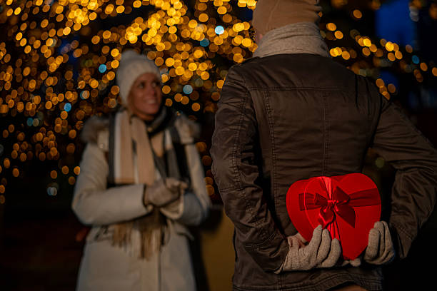 istock Man surprising woman with heart-shaped gift at night 2251082135