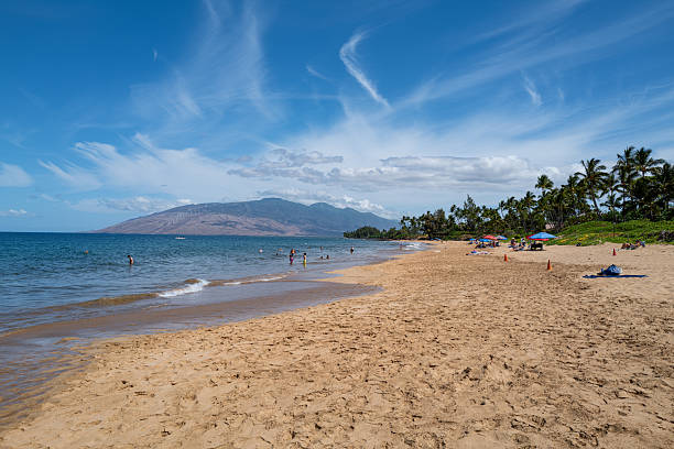 Kihei, HI, U.S.A. - July 21, 2025: View looking north to West Maui at Kamaole I beach showing sandy shoreline, palm trees, and beachgoers enjoying a sunny summer day.