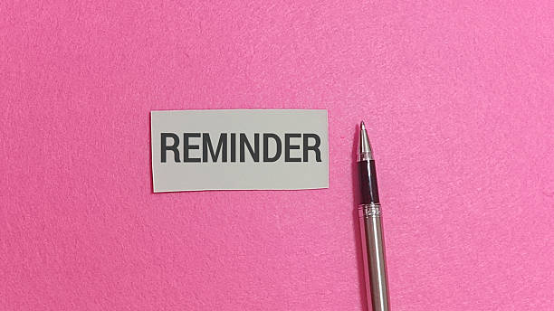 istock Reminder note featuring bold dark text rests prominently upon a vivid pink textured surface. 2251092549
