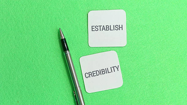 istock Two small white note cards displaying the words establish and credibility are positioned next to a sleek silver. 2251092798