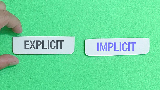 istock Two small white cards labeled explicit and implicit are presented side-by-side on a vibrant green felt surface. 2251092881