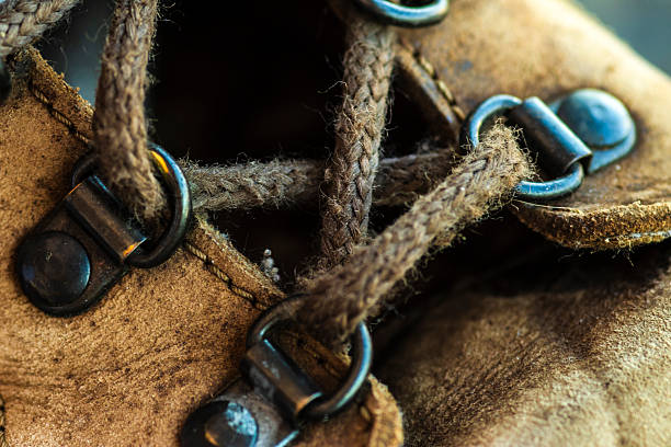 Close-up of a well-worn brown leather hiking boot. Detail of the textured material, sturdy laces, and metal eyelets, suggesting a story of adventure, travel, and durability.