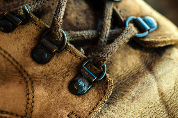 Close-up of a well-worn brown leather hiking boot. Detail of the textured material, sturdy laces, and metal eyelets, suggesting a story of adventure, travel, and durability.