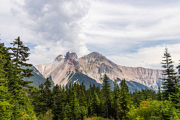 Breathtaking Mountain Peaks Surrounded by Lush Forest and Dramatic Sky in Canada