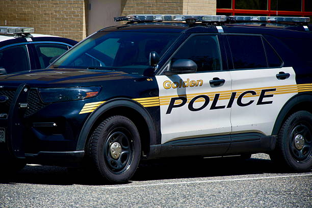 Golden, Colorado, USA - April 26, 2025: Parked Golden Police vehicles in a downtown parking lot sit empty on a sunny day.