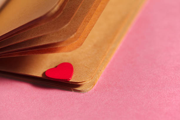 A red Valentine's Day heart hangs by an old nail on a rustic wood wall.