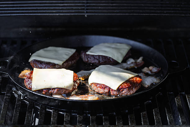 Cheeseburgers sizzling on a griddle, topped with molten cheese, illuminated by warm, natural sunlight. A close-up view capturing the essence of outdoor cooking and appetizing culinary preparations.