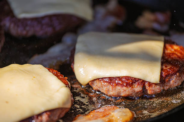 istock Delicious Cheeseburgers Cooking on a Griddle Under Natural Daylight 2251104698