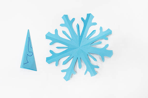 istock A blue snowflake cut out of paper on a white table 2251110313