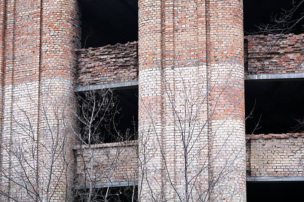 Timeworn brick columns stand tall amid a desolate urban scene, nature creeping in.