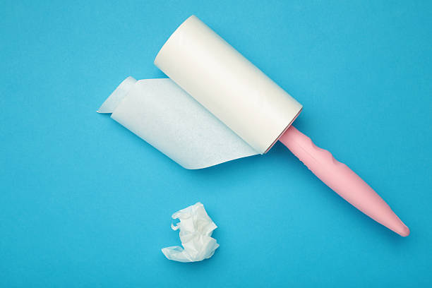 istock Cloth fabrics cleaner lint roller brush with paper roll on blue background. Sticky roller, pet cat dog fur dust hair remover 2251115901