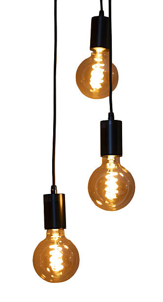 istock Three light bulbs hang down from black cords. The bulbs are lit and give off a warm glow. They are positioned individually but close together against a white surface 2251119634