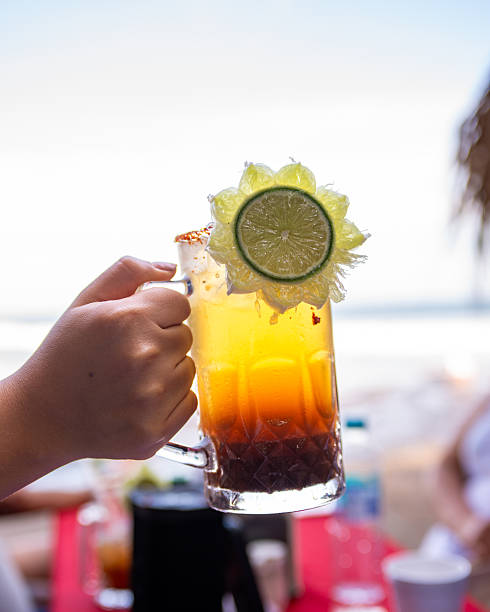 istock Female hand holding a refreshing and colorful Michelada drink garnished with lime. 2251121406