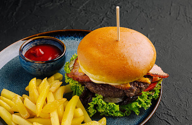 Juicy burger with bacon and fries served on a blue plate