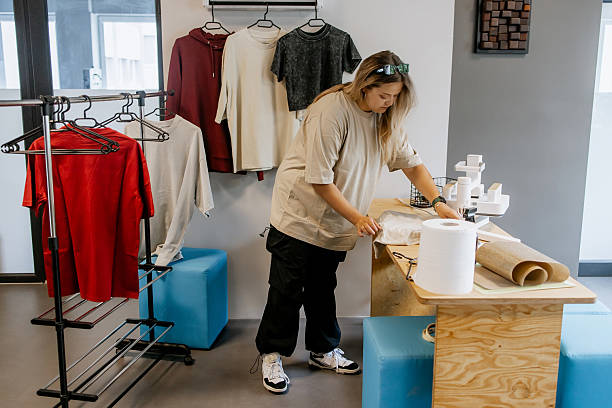 istock Female clothing designer preparing fabric for heat press machine in creative textile workshop, small business production of custom t-shirts and personalized fashion apparel 2251125815