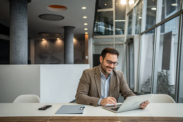 istock Smiling businessman connecting with laptop in modern office 2251127293