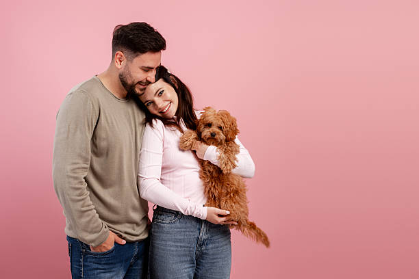 istock Young couple hugging and holding their cute cavapoo puppy, family concept 2251132371