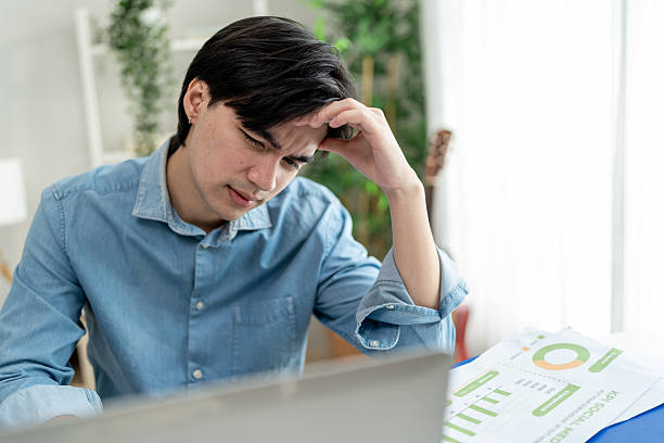 istock Depressed Asian man freelancer using laptop device working in house. Attractive male feel worried and frustrated while overworking and use notebook device communicate online in living room at home. 2251137620