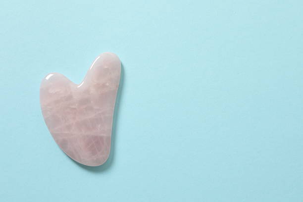 istock Gouache scraping from rose quartz on a pastel background. Natural stone massager, lymphatic drainage massage beauty tools, Chinese therapy. 2251150979