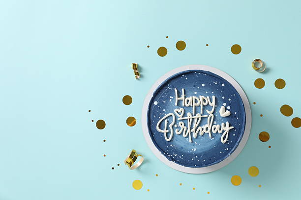 Birthday cake with golden confetti on blue background, top view