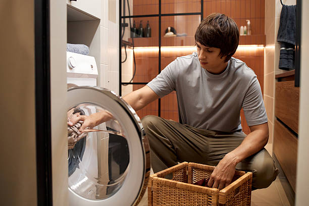 istock Young Man Loading Laundry into Washing Machine in Modern Bathroom 2251154374