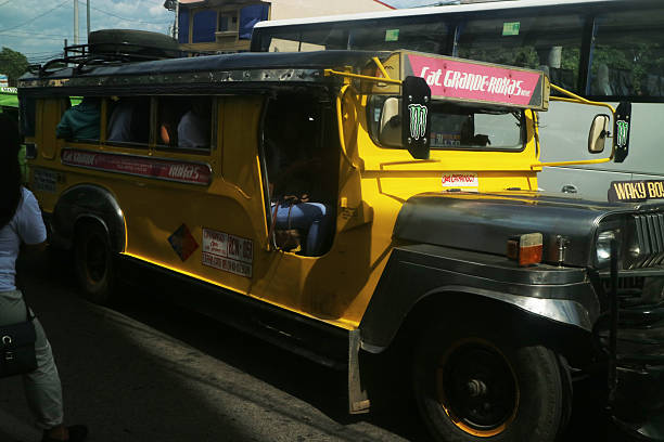 A yellow jeepney operates along the Cat. Grande–Roxas route in the Philippines, with passengers visible inside. Davao City, Philippines on October 19, 2017