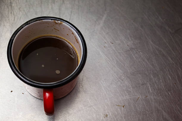 Authentic Greek coffee served in a red enamel mug, placed on a worn metal surface. Rustic and minimal composition, ideal for editorial content, Greek culture, and everyday moment